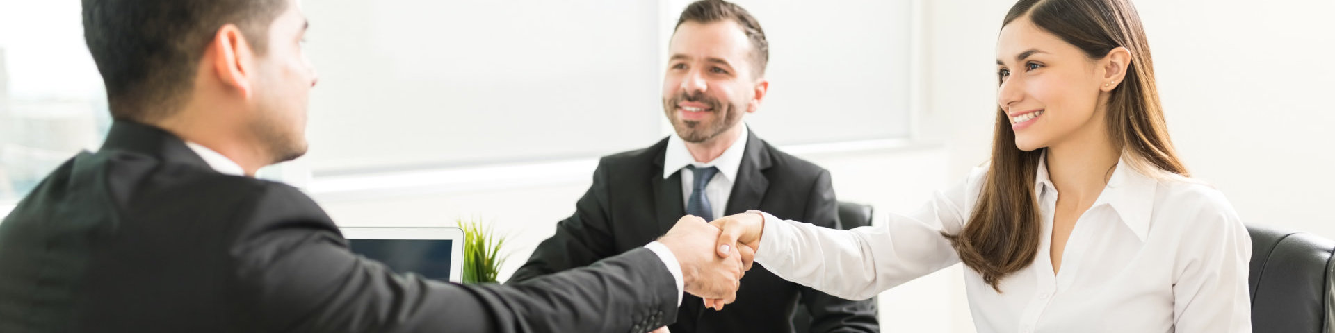 Smiling businesswoman shaking hand with employee at desk in office